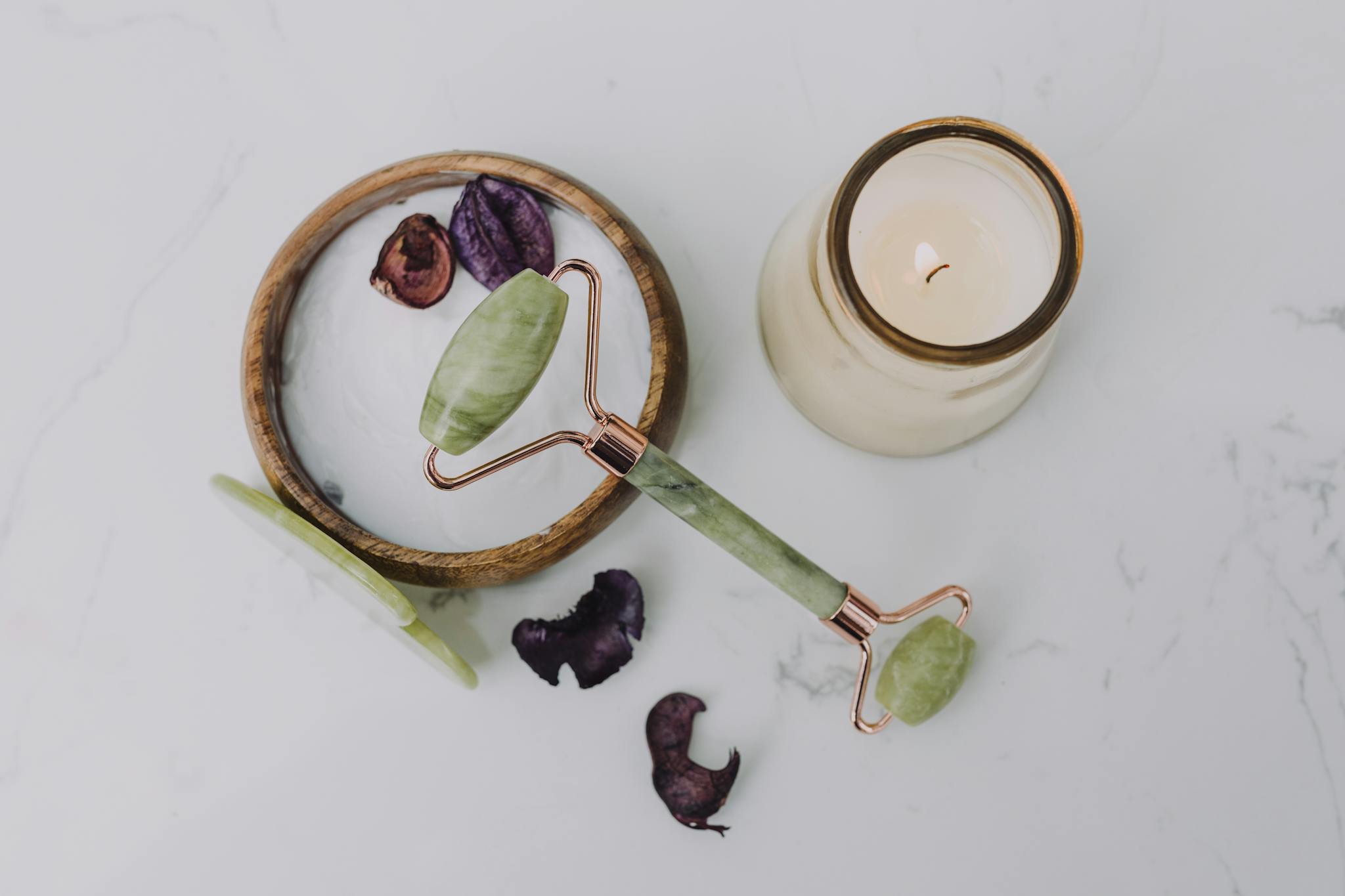 A relaxing flat lay of a jade roller and candle, perfect for a spa day at home.